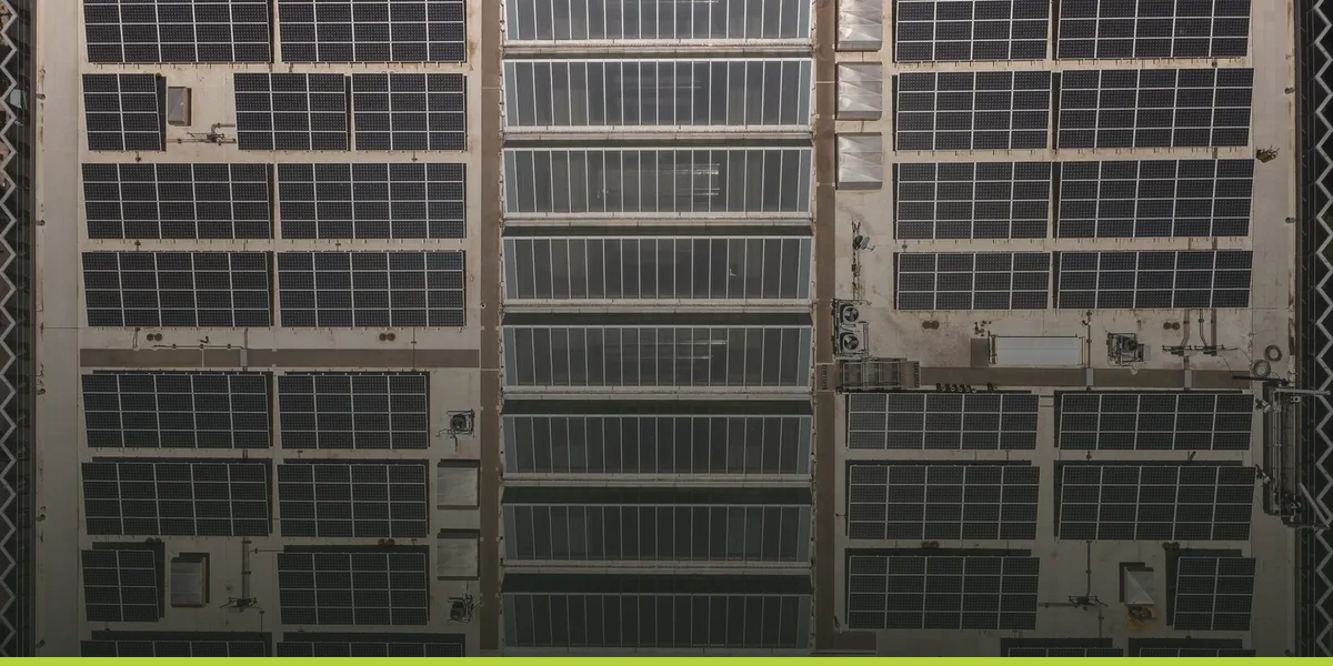 Aerial view of solar panel arrays covering the full roof of an industrial facility